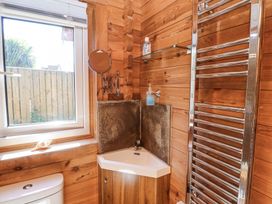 A small corner sink with soap and hand gel a towel radiator and a window in a wooden bathroom at Aurora Skies in Cresswell near Morpeth