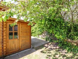 A wooden shed next to a stone wall covered with green ivy and trees at Aurora Skies in Cresswell near Morpeth