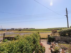 A garden with hedges and flowers overlooking a road and fields at Aurora Skies in Cresswell near Morpeth
