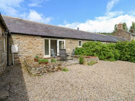 A garden with a stone patio and chairs at Gallow Law Cottage in Bellingham