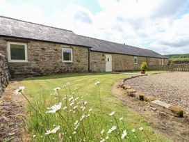 A stone building with windows and grass at Shepherds Burn Cottage in Bellingham