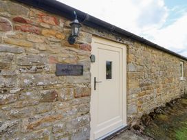 An entrance with stone wall and door at Shepherds Burn Cottage in Bellingham