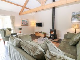 A living room with a sofa, armchair, and wood stove at Shepherds Burn Cottage in Bellingham