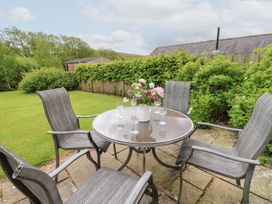 A table with chairs and a vase of flowers in the garden at Shepherds Burn Cottage in Bellingham
