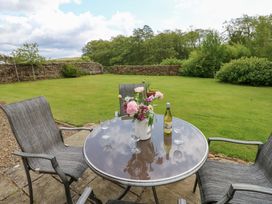 A table with chairs and flowers in a garden at Shepherds Burn Cottage Bellingham