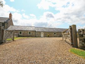 An outdoor area with a gravel driveway and a stone building at Shepherds Burn Cottage Bellingham