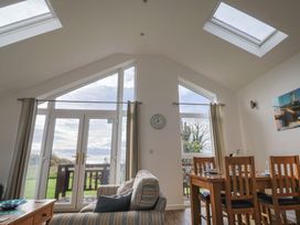 A living room with a dining area and large windows at Keepers Cottage in Sidmouth