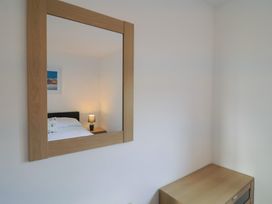 A bedroom with a bed and lamp visible in the mirror at Keepers Cottage Sidmouth