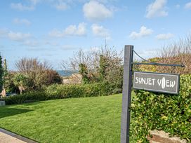A sign for Sunset View near grass and trees in Porth