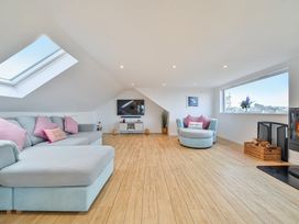 A living room with a sofa, television, and fireplace at Sunset View in Porth