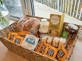 A basket containing bread, milk, shortbread, strawberry jam, and tea bags at Sunset View in Porth