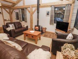 A living room with sofas, a table, a fireplace and a television at Lady Bagots Cabin in Ruthin