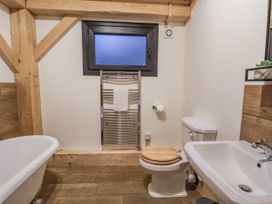 A bathroom with bathtub, toilet, towel rack, and sink at Lady Bagots Cabin in Ruthin