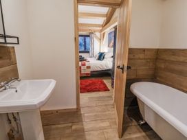 A bathroom with a sink and bathtub leading to a bedroom at Lady Bagots Cabin in Ruthin