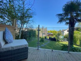 A garden view with outdoor seating and a glass railing at Hearthstone East Cottage in Brixham
