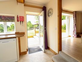 A kitchen entrance with a dishwasher and an open door at Mallows Byre in Yetminster