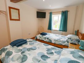 A bedroom with two beds and a television at Mallows Byre in Yetminster