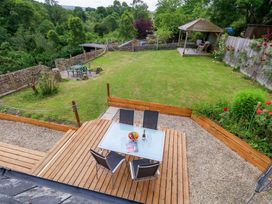 A garden with a table and chairs overlooking green space at Mallows Byre in Yetminster