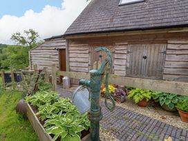 A water pump and plants outside a wooden building at Mallows Byre in Yetminster