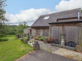 A wooden building with potted plants and a pathway at Mallows Byre in Yetminster