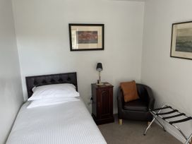 A bedroom with a bed, nightstand, lamp, and a chair at The Coach House in Bodmin