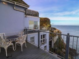 An outdoor patio with a table and chairs overlooking the ocean at Close to Shore