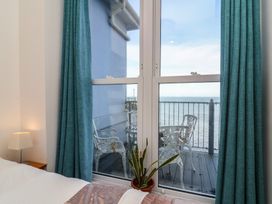 A bedroom with window view of a deck and sea at Close to Shore