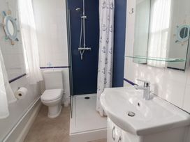 A bathroom with shower, sink, toilet, and mirror at Close to Shore