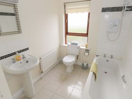 A bathroom featuring a bathtub, toilet, sink, and window at Aisling in Foxford near Ballina, County Mayo