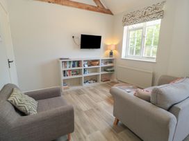 A living room with a television and bookshelves at The Cider Press, Motcombe