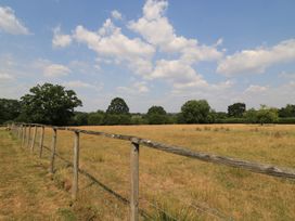 A field with a wooden fence and trees at The Cider Press, Motcombe