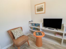A living room with a chair, television, and bookshelf at The Apple Shed, Motcombe