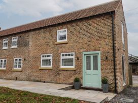 Brick house with multiple windows and a light green front door with two potted plants at Winnie's Stable Goodmanham Wold near Market Weighton