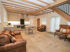A kitchen and living area with wooden beams on ceiling a dining table leather sofas and an armchair at Winnie's Stable Goodmanham Wold near Market Weighton