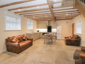 An open kitchen and living area with exposed wooden beams two leather sofas a wooden table and chairs and a white refrigerator at Winnie's Stable Goodmanham Wold near Market Weighton