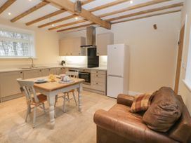 A kitchen with wooden beams on the ceiling a wooden table two chairs a leather armchair and white cabinets at Winnie's Stable Goodmanham Wold near Market Weighton