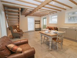 A kitchen dining area with a wooden table and chairs leather armchairs a staircase and exposed ceiling beams at Winnie's Stable in Goodmanham Wold near Market Weighton
