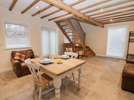 A dining area with a wooden table set for two and leather armchairs near a staircase in a room at Winnie's Stable Goodmanham Wold near Market Weighton