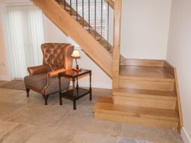 A leather armchair with a side table and lamp next to wooden stairs at Winnie's Stable in Goodmanham Wold near Market Weighton