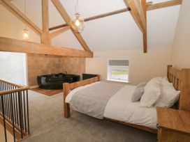 A bedroom with a wooden bed and a black bathtub under wooden beams at Winnie's Stable in Goodmanham Wold near Market Weighton