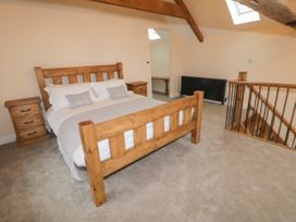 A bedroom with a wooden bed, bedside tables, a black radiator, and a staircase with wooden railings at Winnie's Stable in Goodmanham Wold near Market Weighton