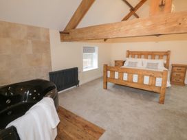 A bedroom with a wooden bed and side tables and a black bathtub with a white towel at Winnie's Stable Goodmanham Wold near Market Weighton