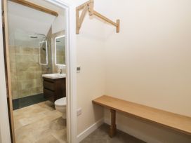 A hallway with a wooden bench and hanging rail next to a bathroom with a walk-in shower at Winnie's Stable in Goodmanham Wold near Market Weighton