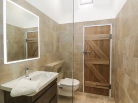 A bathroom with a sink cabinet a lit mirror a towel a toilet and a wooden door at Winnie's Stable Goodmanham Wold near Market Weighton