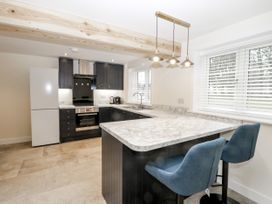 A kitchen with marble countertops blue bar stools black cabinets and a white refrigerator at The Groom's Cottage in Goodmanham Wold near Market Weighton