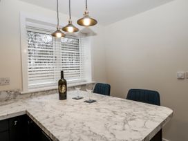 A kitchen area with a marble countertop table two blue chairs a wine bottle and two wine glasses under hanging lights at The Groom's Cottage in Goodmanham Wold near Market Weighton