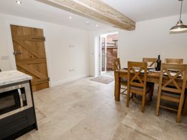 A kitchen dining area with a wooden table and six chairs a wooden door a marble countertop microwave and a door opening to an outdoor patio at The Groom's Cottage Goodmanham Wold near Market Weighton