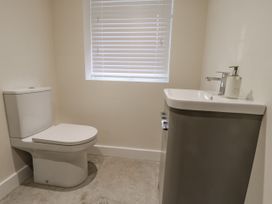 A bathroom with a toilet and a sink under a window with blinds at The Groom's Cottage in Goodmanham Wold near Market Weighton