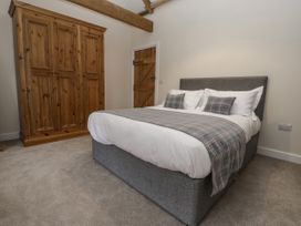 A bedroom with a gray upholstered bed and wooden wardrobe at The Groom's Cottage Goodmanham Wold near Market Weighton