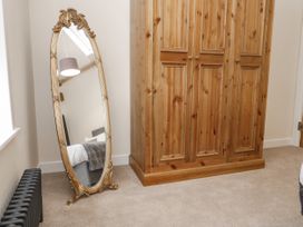 A bedroom corner with a wooden wardrobe and a standing ornate mirror reflecting a bed at The Groom's Cottage Goodmanham Wold near Market Weighton